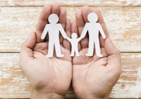 person-holding-paper-family-hands-wooden-background | Foto: freepik.com