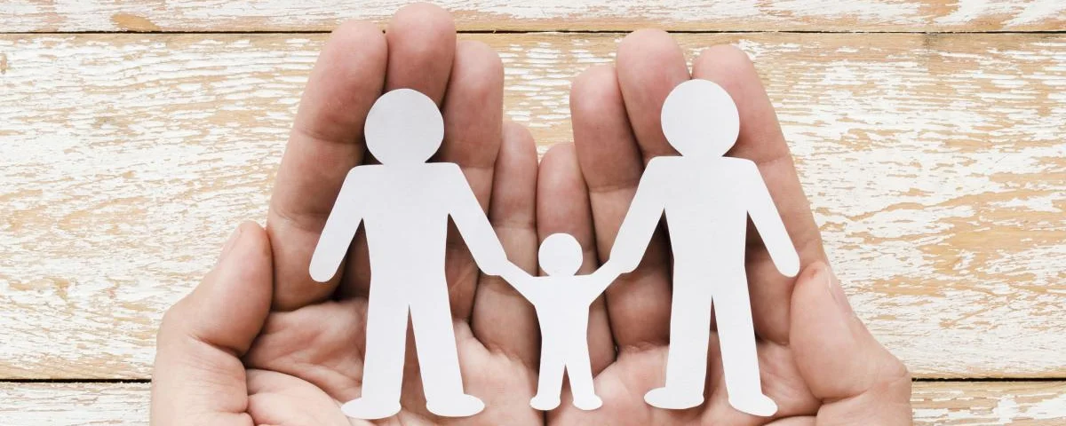 person-holding-paper-family-hands-wooden-background